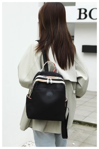 Detail of black oxford cloth backpack featuring ethnic patterned trim and side pockets