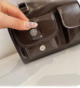 Detail of dark brown glossy leather shoulder bag with silver magnetic snap pocket