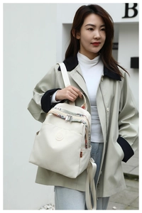 Close-up of cream oxford backpack with colorful ethnic ribbon and side pocket detail