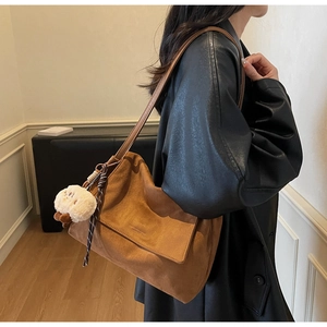 Detail view of vintage brown faux suede tote bag with cute plush bear charm on a model