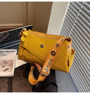 Detail of yellow nylon crossbody bag with multi-zipper layers and wide printed strap