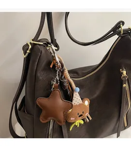 Detail of dark brown leather tote bag featuring a star pendant and a cute bear toy accessory