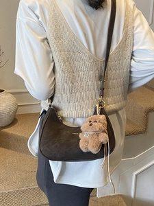 Deep brown crescent moon crossbody bag with suede finish and cute plush bear charm