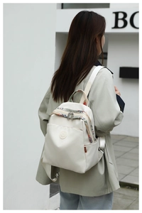 Detail of off-white backpack with colorful ethnic patterns on handles and zippers