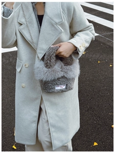 Close-up of light grey plush shoulder bag with fluffy faux fur and metal chain strap