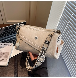 Detail view of cream small square crossbody bag with patterned jacquard wide strap