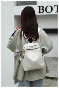 Detail of cream Oxford backpack showing ethnic embroidery trim and circular logo patch