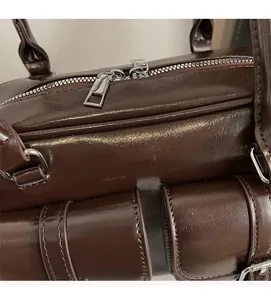 Detail view of smooth dark brown oiled leather bag with silver double zippers and hardware