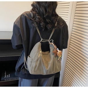 Détail d'un sac à dos rétro gris foncé en similicuir souple avec pendentif d'ours