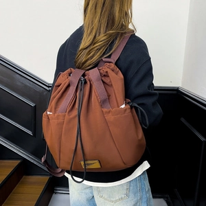Detail of a brown drawstring backpack with durable nylon fabric and side storage pockets
