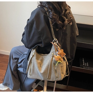 Detail of olive green hobo bag featuring decorative zippers, long tassels and cute charms
