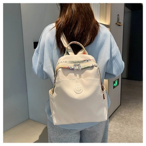 Detail of cream Oxford fabric backpack with ethnic embroidery and side pockets on model