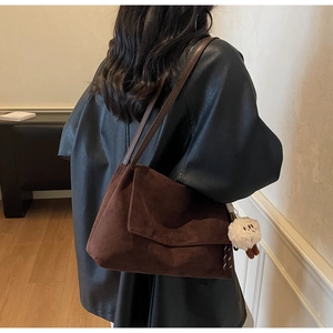 Brown suede tote bag with plush charm shown from behind on a model shoulder