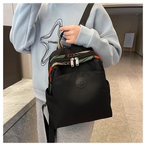 Detail of black oxford backpack featuring ethnic floral embroidery and circular logo plaque