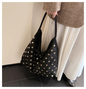 Close-up of black suede tote bag with decorative gold studs and soft texture