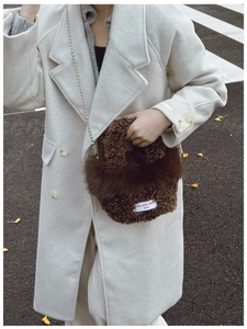 Detail of a brown fuzzy lamb wool shoulder bag featuring a chic silver bead chain strap