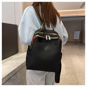 Detail of black nylon backpack featuring colorful ethnic jacquard ribbon and top handle