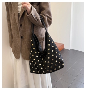 Detail of vintage black suede hobo bag with gold rivets worn with a brown blazer