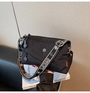 Detail of black nylon shoulder bag featuring SJCHAO lettered strap and orange woven label