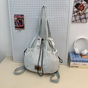 Detail of light gray nylon drawstring backpack hanging on a white pegboard organizer