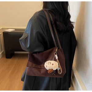 Detail of dark brown tote bag with leather strap and plush mushroom charm