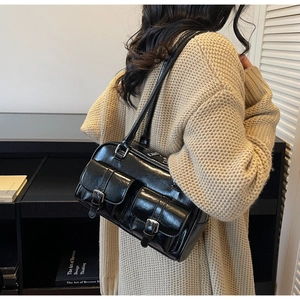 Detail of vintage black glossy Boston bag with buckle pockets held by a model