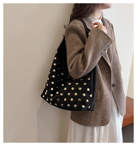 Close-up of black rivet tote bag showing gold studs and matte suede texture on model