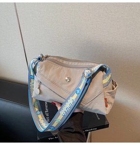 Detail of beige nylon crossbody bag featuring multi-pocket design and wide colorful strap