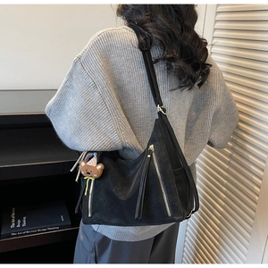 Vue détaillée du sac Hobo noir avec fermetures éclair argentées et charm d'ours peluche