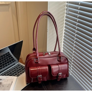 Detail of burgundy leather Boston bag with silver buckles in office setting