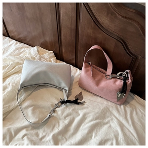 Détail de sacs hobo bleu clair et rose avec texture suédée et breloques en métal en cœur