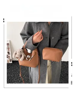 Detail of vintage brown bucket bag with lychee texture and plush rabbit keychain