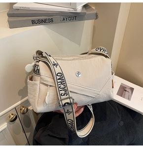 Detail view of beige nylon crossbody bag showing zip pockets and logo strap