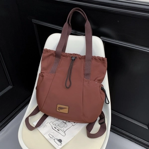 Detailed view of brown waterproof nylon backpack with drawstring and logo on a white chair