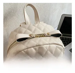 Détail du mini sac à dos en cuir PU matelassé beige avec clous dorés et un nœud