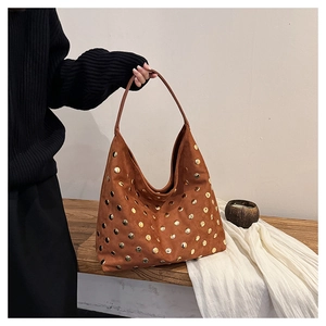 Detail of a large brown suede hobo bag with gold metal rivets and wide shoulder strap