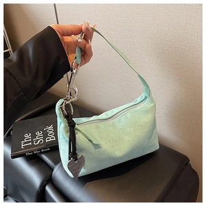 Détail du sac en daim vert menthe avec fermeture éclair argentée et pendentif en forme de cœur