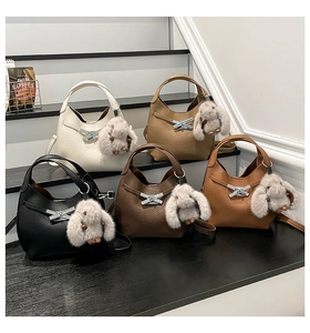 Various colors of vintage bucket bags with metal locks and plush rabbit charms on steps