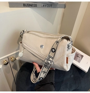 Detail of beige nylon crossbody bag with multi-zipper compartments and floral jacquard strap
