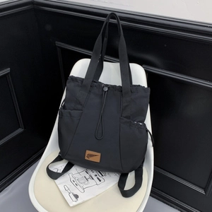 Detail of a versatile black nylon tote bag featuring a drawstring closure and side pockets
