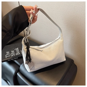 Détail du sac demi-lune en daim blanc avec pendentif cœur argenté et bandoulière