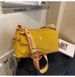 Detail of yellow nylon crossbody bag featuring textured fabric and wide printed strap