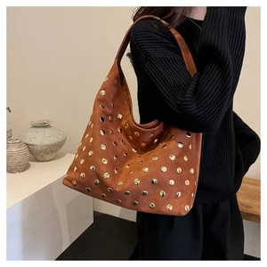 Close-up of vintage brown suede tote bag featuring polished gold stud details