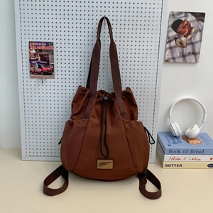 Detail of a brown drawstring backpack with hand straps and side storage pockets