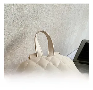Vue détaillée du sac à dos matelassé en similicuir crème avec poignée et fermoirs dorés