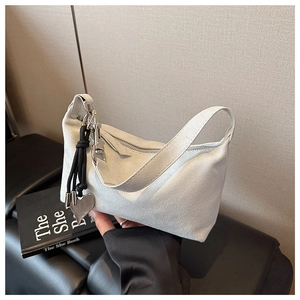 Détail d'un sac hobo en daim blanc cassé avec fermeture éclair argentée et breloque cœur