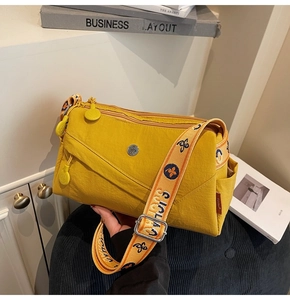 Detail view of yellow nylon crossbody bag with multiple zip pockets and jacquard strap