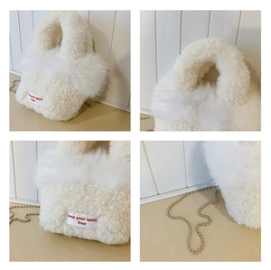 Detail of white fluffy plush tote bag with embroidered slogan and silver bead chain
