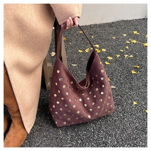 Close-up of vintage brown suede tote bag featuring detailed gold rivet embellishments