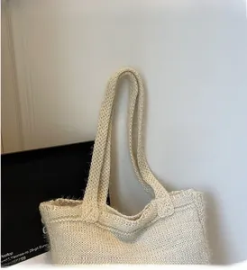 Close-up of beige knitted tote bag featuring a thick cable knit texture and soft handles